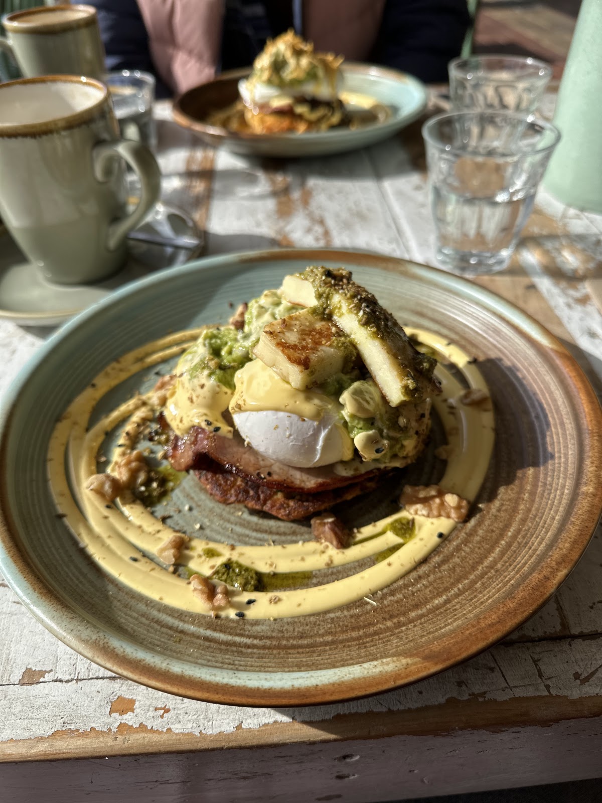 Eggs benedict with haloumi, avocado and walnuts in morning light