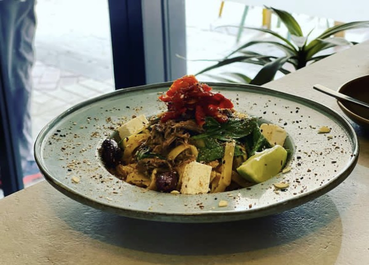 A tagliatelle bowl with olives, spinach and soft cheese by the window
